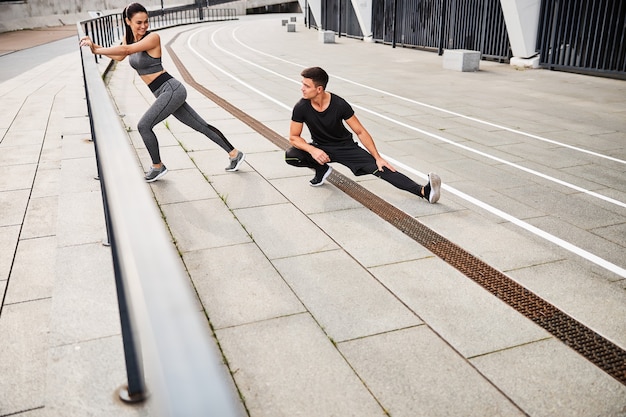 Feliz hermosa mujer y hombre deportivo pasan tiempo activo y hacen ejercicio en el centro de la ciudad