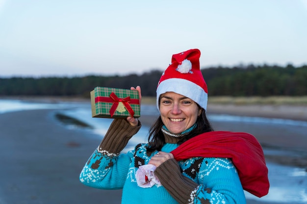 Feliz hermosa mujer joven en una gorra de Navidad saca regalos de Navidad de la bolsa celebra