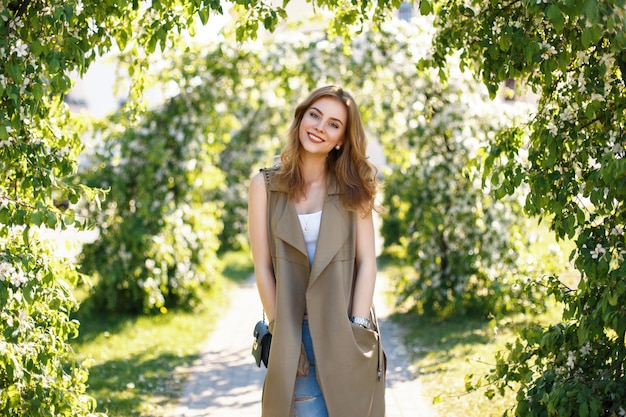 Feliz hermosa mujer con linda sonrisa en ropa de moda en el parque en un día soleado de primavera