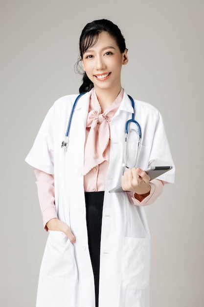 Feliz hermosa mujer trabajadora asiática en ropa de oficina sonriendo y sobre fondo gris aislado