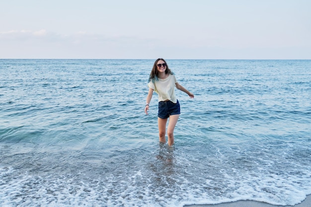 Feliz hermosa niña adolescente sonriente disfrutando de la naturaleza del mar de agua de mar