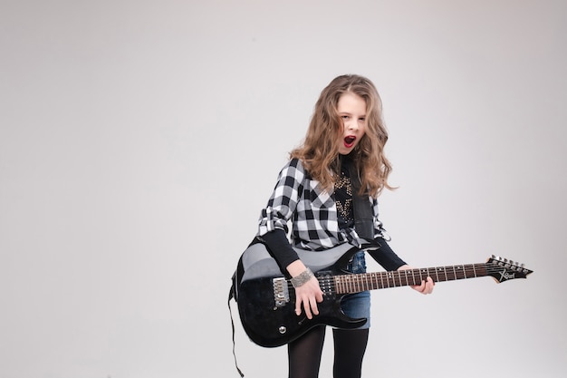 Feliz hermosa niña artística pequeña tocando la guitarra