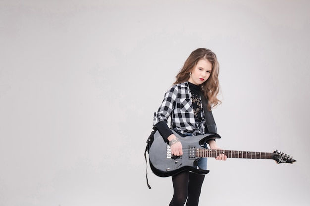 Feliz hermosa niña artística pequeña tocando la guitarra