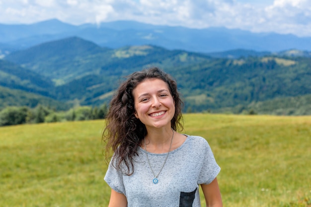 Feliz hermosa niña disfruta de la vista a la montaña, quédate en la colina con un impresionante paisaje de montaña