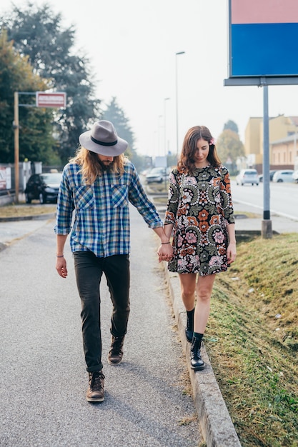 Feliz hermosa pareja de enamorados caminando por pasaje agujereando las manos