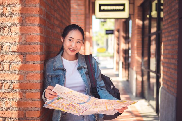 Feliz hermoso turista joven mujer asiática con mochila en hombros explorar mapa