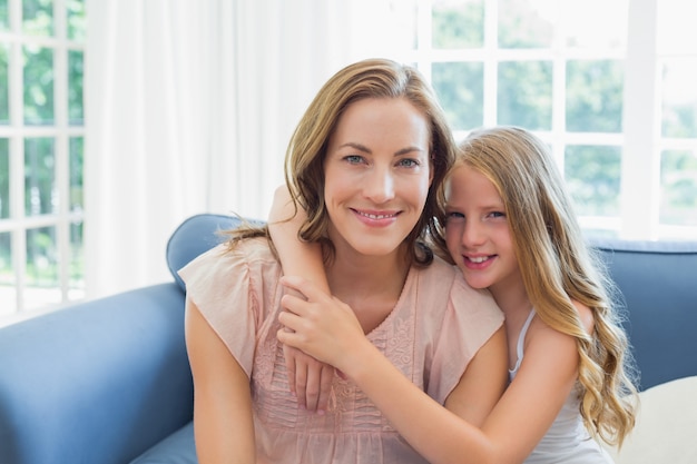 Feliz hija abrazar a la madre en la sala de estar