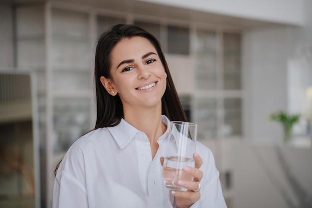 Foto feliz hispano confiado con cabello oscuro suelto en camisa blanca con una hermosa sonrisa mira a la cámara