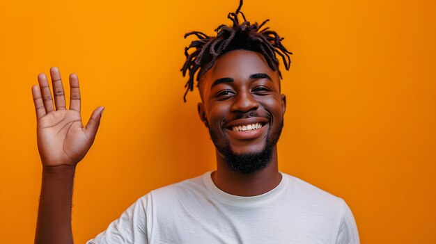 Feliz hombre afroamericano con rastas agitando la mano sobre fondo amarillo