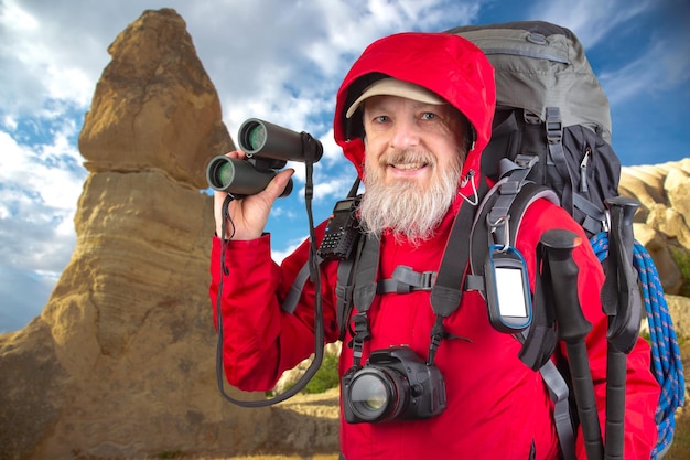 Foto feliz hombre barbudo viajero con equipo de senderismo en el fondo del paisaje de montaña