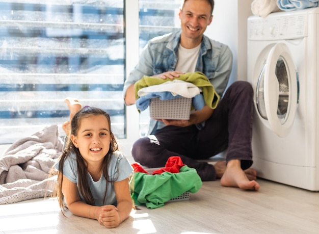Feliz hombre de familia padre amo de casa y niño hija en lavandería con lavadora