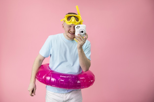 Foto feliz hombre con máscara de natación amarilla y con anillo de goma hacen foto instantánea