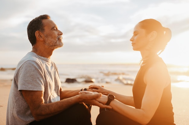 Feliz hombre y mujer caucásicos maduros en ropa deportiva sentarse practicar yoga meditar en la mañana