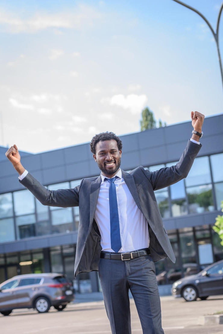 Foto feliz hombre de negocios afroamericano mostrando el gesto del ganador mientras mira a la cámara