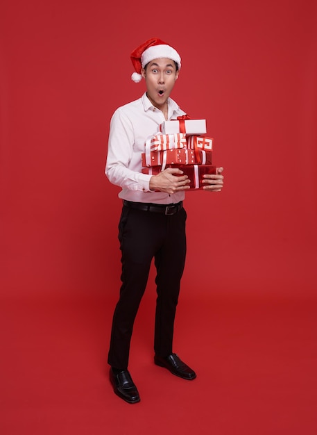 feliz hombre de negocios asiático con sombrero de Santa sosteniendo una pila de cajas de regalos celebración de Navidad