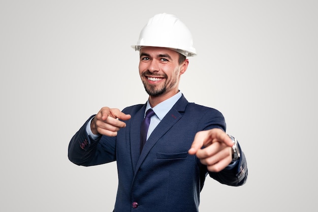 Feliz hombre de negocios en casco apuntando a la cámara