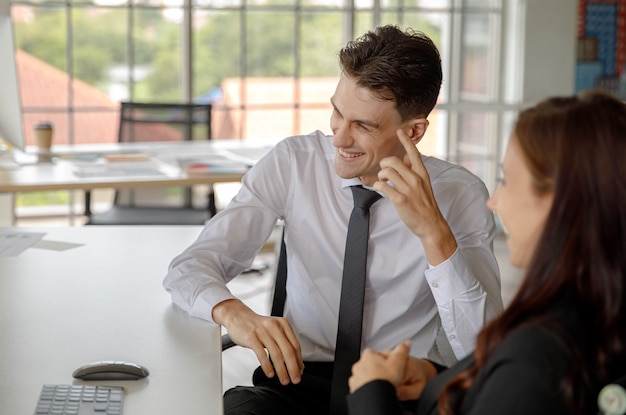 Feliz hombre de negocios caucásico y empresaria empleado personal trabajador oficial sentado sonriendo riendo hablando tener conversación sobre un breve descanso juntos en la mesa de trabajo en el lugar de trabajo de la oficina de la empresa.