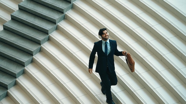 Feliz hombre de negocios escuchando música con auriculares mientras camina exultante