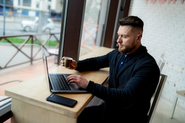 Feliz hombre de negocios sentado y trabajando en un acogedor café con una taza de café