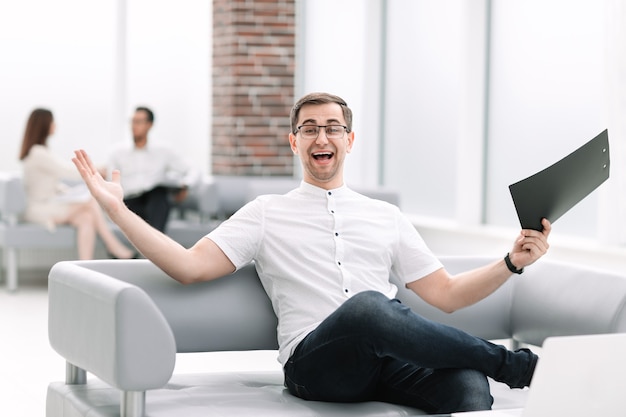 Feliz hombre de negocios sentado en el vestíbulo del banco