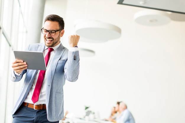 Feliz hombre de negocios con tableta en la oficina