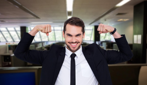 Feliz hombre de negocios en traje animando contra la oficina vacía con unidades separadas