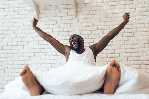 Feliz homem acordado é estendido na cama.