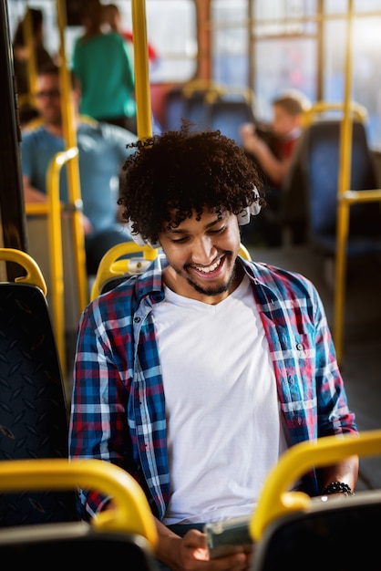 Feliz homem afro-americano bonito sentado em um ônibus e ouvir a música.