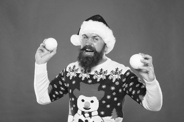 Foto feliz homem barbudo com suéter de malha quente e chapéu de papai noel segura bolas de neve decorativas para comemorar o feriado de inverno do natal ano novo decoração da árvore