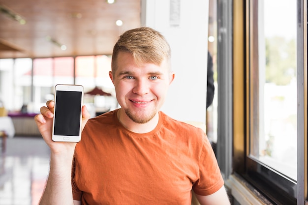 Feliz homem casual, mostrando a tela do smartphone em branco