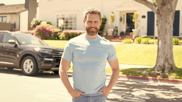 Feliz homem confiante fica na nova casa e carro