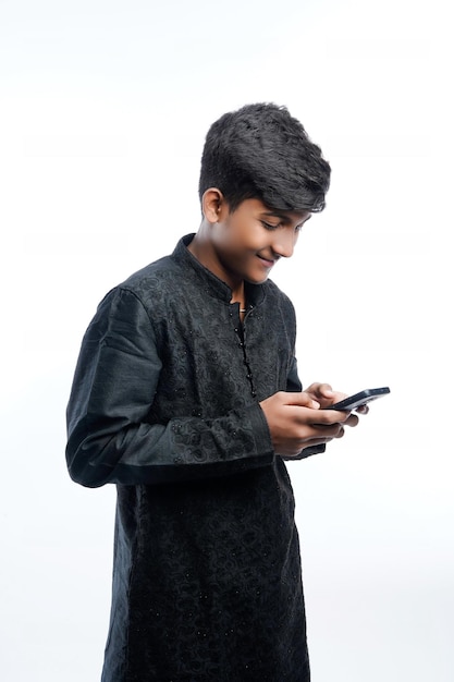 Feliz homem indiano bonito vestindo roupa étnica segurando ou usando telefone celular celebrando o festival diwali e dando expressão