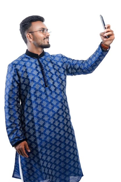 Feliz homem indiano bonito vestindo roupa tradicional segurando ou usando telefone celular celebrando o festival diwali e dando expressão