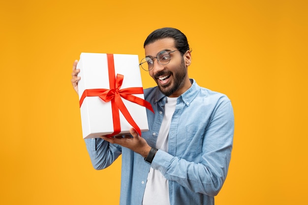 Feliz homem indiano milenar com barba e óculos compartilhando ideia para presente de show