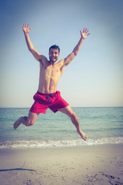 Feliz homem pulando na praia