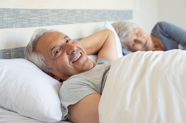 Foto feliz homem sênior, deitado na cama