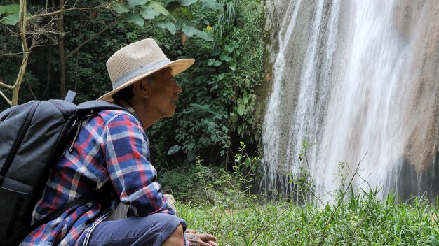 Feliz, homem sênior, sentando, perto, cachoeira, desfrutando, deslumbrante, vista