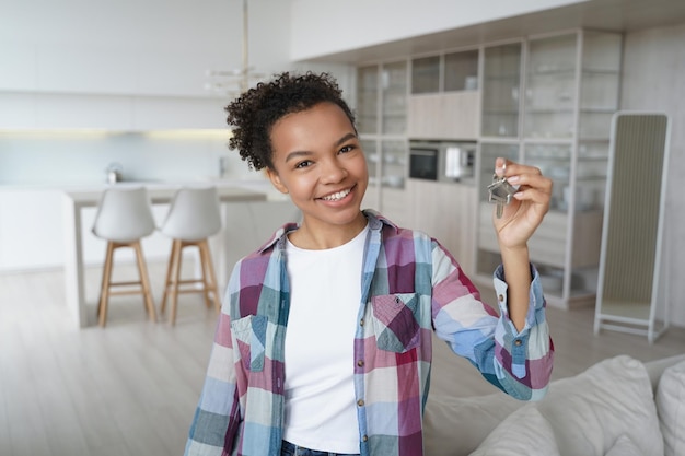 Foto feliz inquilino do proprietário da jovem garota biracial mostra a chave para a nova casa aluguel de imóveis de realocação