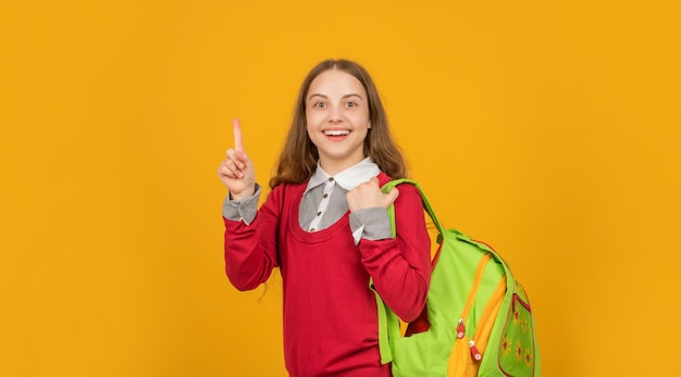 Feliz inspirado com a ideia de uma adolescente com mochila escolar na escola de fundo amarelo