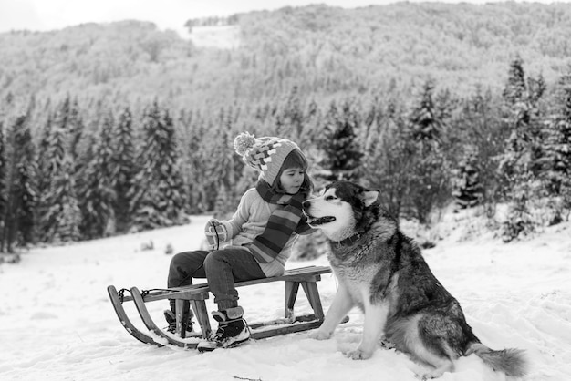 Feliz invierno niño niño perro malamute de alaska y cabrito en invierno de nieve austria o canadá