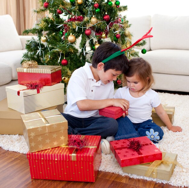 Feliz irmão e irmã abrindo presentes de Natal