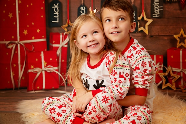 Feliz irmão e irmã de pijama de Natal à espera de presentes na véspera de Natal