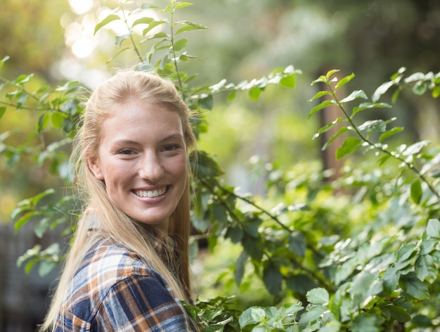 Feliz jardineiro feminino em pé por plantas