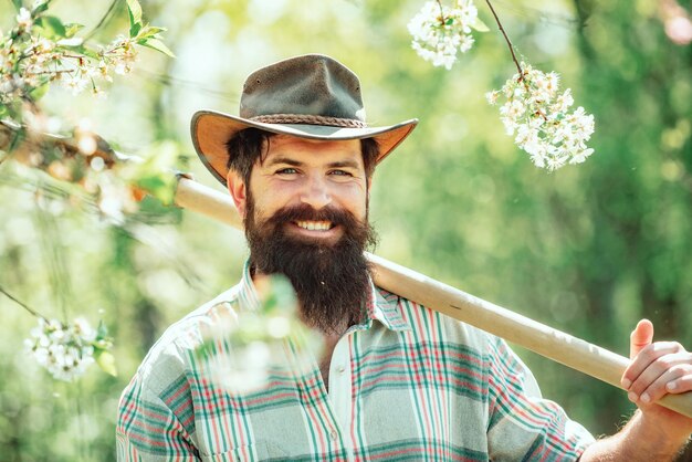 Feliz jardinero trabaja en el jardín con herramientas de jardín y pasa un buen rato granjero trabajando en el campo de primavera y