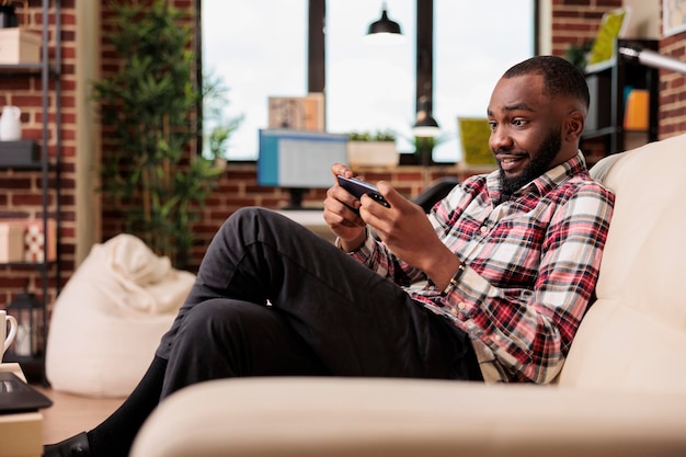 Feliz jogador virtual se divertindo com videogames, jogando competição online no aplicativo para smartphone. Usando o telefone celular e desfrutando de jogos na internet, fazendo trabalho freelance remoto.