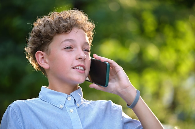 Feliz jovem adolescente falando no celular ao ar livre no parque de verão Conceito de amizade online