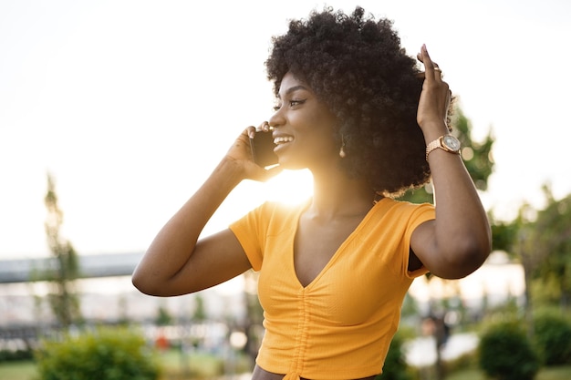 Feliz jovem afro-americana falando com celular na cidade