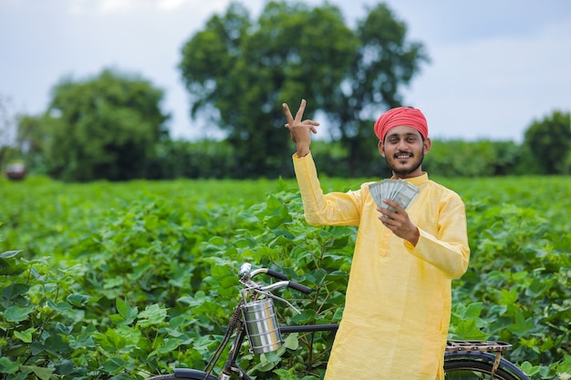 Feliz jovem agricultor indiano contando e mostrando dinheiro