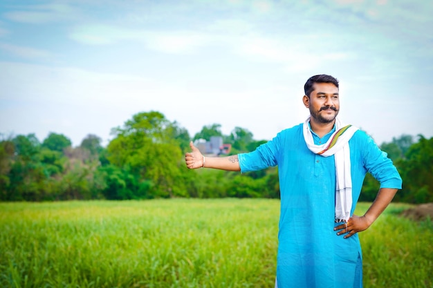 Feliz jovem agricultor indiano mostrando a mão no campo de cana-de-açúcar 1