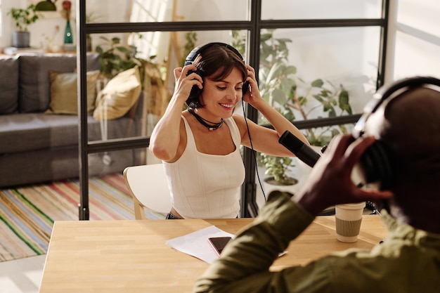 Feliz jovem anfitriã e seu convidado afro-americano colocando fones de ouvido